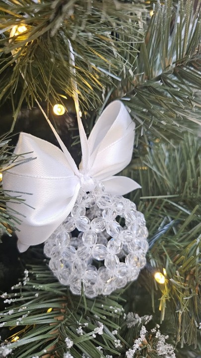 Ręcznie wykonana bombka z transparentnych koralików z białą wstążką, średnica 5–6 cm – elegancka świąteczna dekoracja handmade.